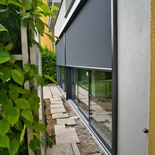 Schiebeanlage mit halb ausgefahrener Zip-Senkrechtmarkise Seitenansicht